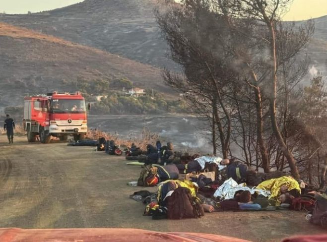 Εξαντλημένοι πυροσβέστες ξαπλώνουν στο χώμα για να ξεκουραστούν στην Κερατέα